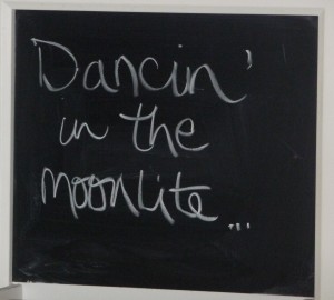 "Dancin in the moonlite" written on a chalkboard