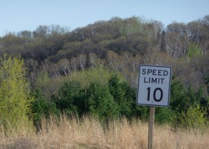 Speed limit 10 mph sign with wooded bluff in the background Speed limit 10 mph sign with wooded bluff in the background